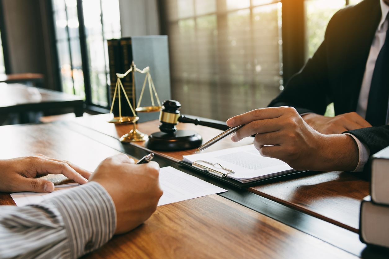 A lawyer reviews paperwork with a client with gavel in background.