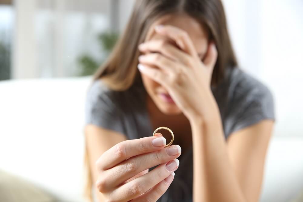 Woman holding her wedding ring, worried about divorce
